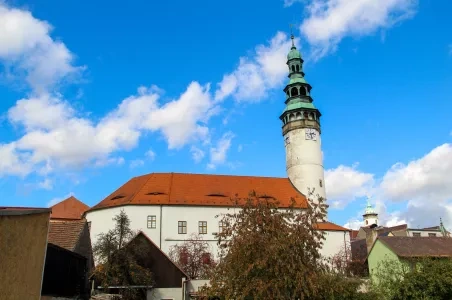 Bílá kostel s vysokou věží v Domažlicích pod modrou oblohou