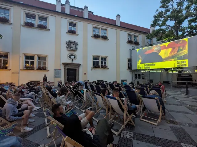 Venkovní kino v Brně s diváky na lavičkách před velkou plátňovou obrazovkou.