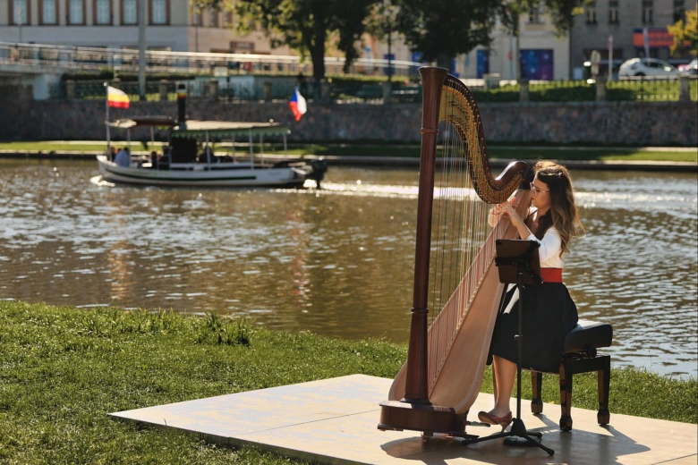 Harpist hraje na řece v Hradci Králové během kulturní akce.