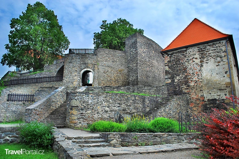 Kamenný hrad s červenou střechou a zahradami