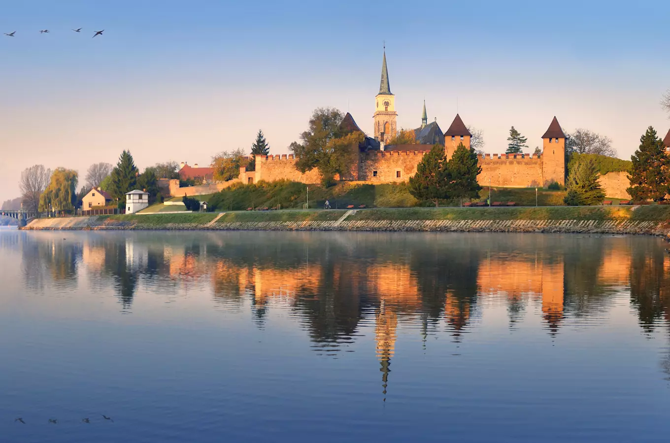 Zámek v Nymburku s kostelem odrazem ve vodě řeky.