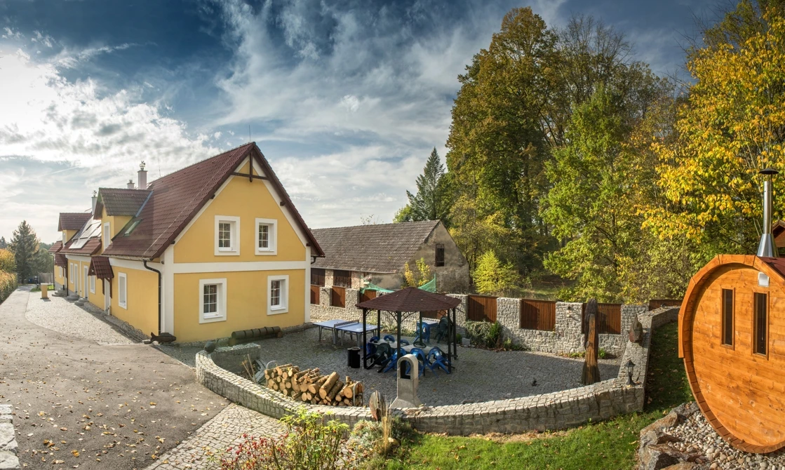 Žlutý dům s hřištěm pro děti a saunou v českém venkovském prostředí.