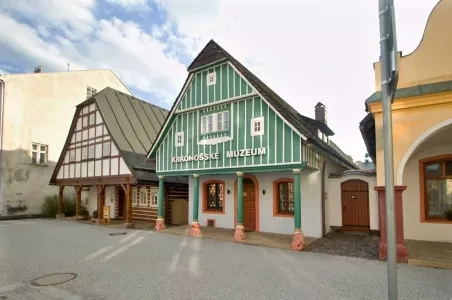 Zelená dřevěná budova muzea ve Vrchlabí na náměstí.