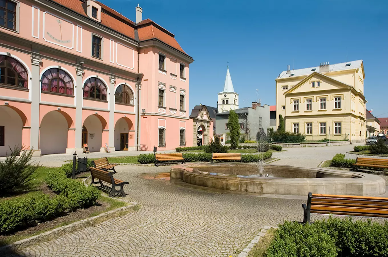 Náměstí s fontánou a historickými budovami ve Valašském Meziříčí