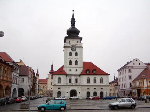 Rathaus ve Žatci s věží na náměstí obklopené historickými domy.