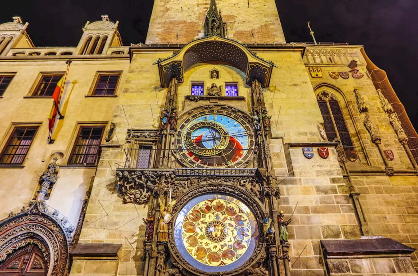 Pražský orloj na radnici v noci s detailními ciferníky.