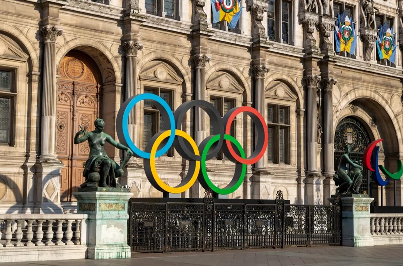 Velké sochy olympijských prstenů před historickou budovou.