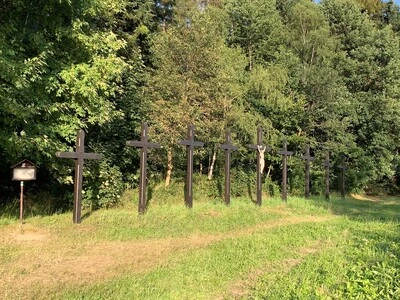 Devět dřevěných křížů na svahu v lese u motorestu