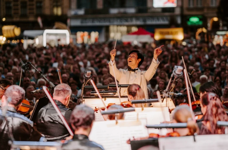 Dirigent vede orchestr v plzni před davem na kulturním programu.