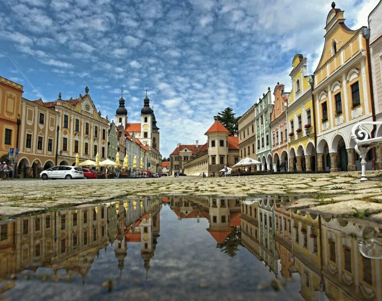 Historické náměstí v Telči s odrazem budov ve vodě.
