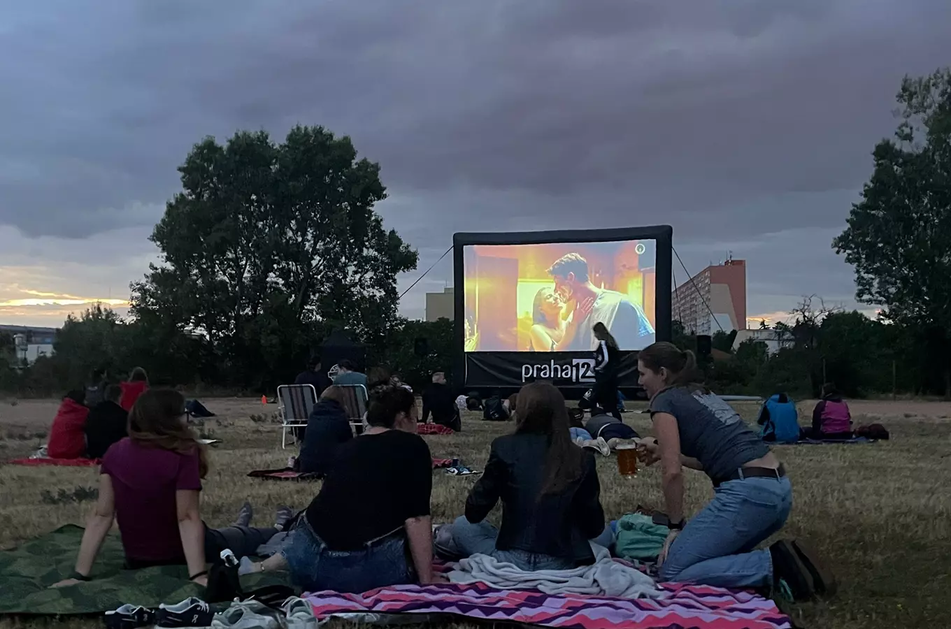 Venkovní kino v Praze s filmem na plátně za soumraku.