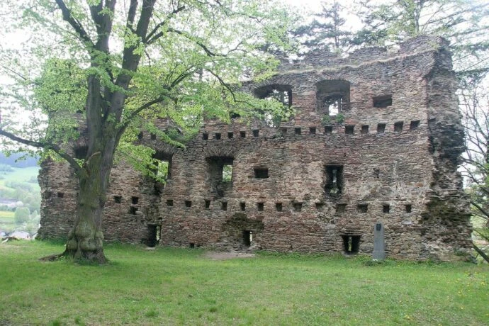 Zřícenina hradu v Bystřici nad Pernštejnem na travnatém svahu.
