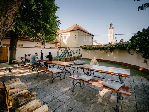 Venkovní terasa restaurace v Kutné Hoře s dřevěnými stoly.