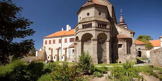 Historická kostelní věž v Třebíči na slunečním zahradním pozadí.