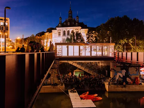 Večerní kulturní akce s diváky na břehu řeky v Plzni.
