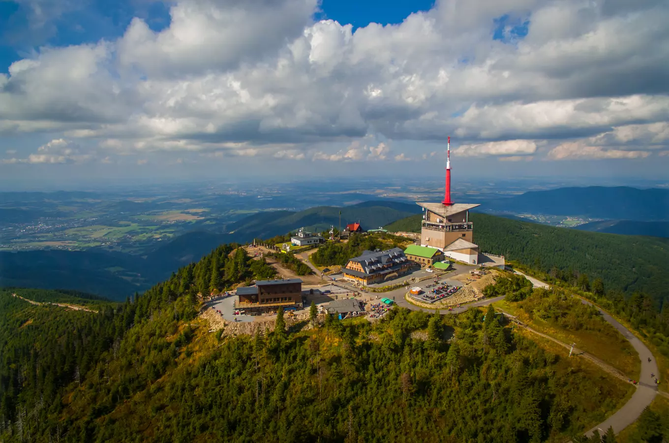 Vrchol hor s výhledem na Beskydy, turistické budovy a věž.