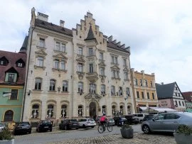 Historické radnice v Lokti na náměstí s parkujícími auty.