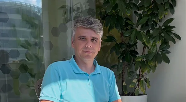 Muž v modrém tričku sedí u rostliny.