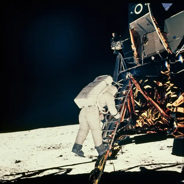 Astronaut sestupuje po žebříku na povrchu Měsíce.