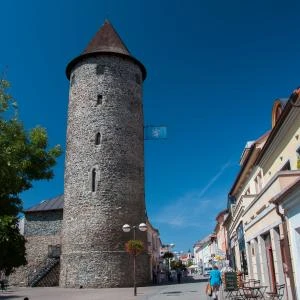 Historická kamenná věž na náměstí v Čáslavi pod modrou oblohou.