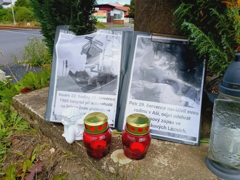 Památník Petra Šepého s fotografiemi svíčkami na silnici.