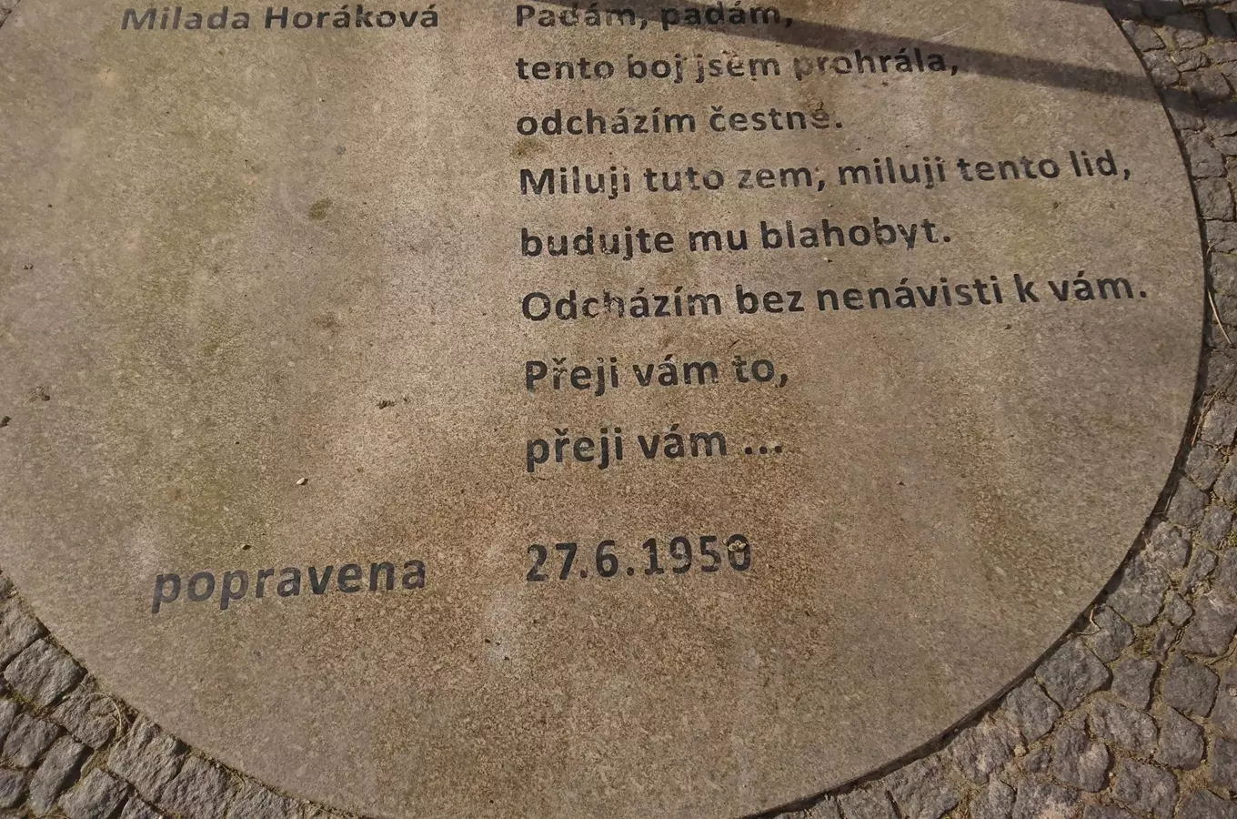 Pamětní deska s veršem Milady Horákové na dlažbě.