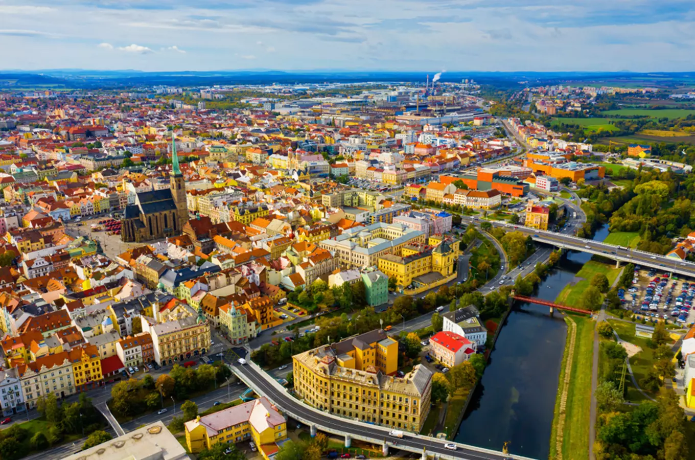 Vzdušný pohled na historické centrum Plzně s řekou a okolní krajinou.