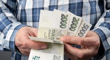 Ruce drží české bankovky jako ilustrace k tématu mzdy.