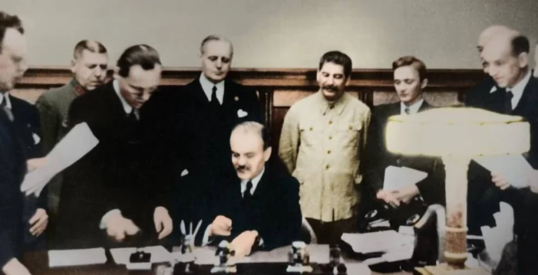 Stalin podepisuje dokument s dalšími muži v historickém snímku.