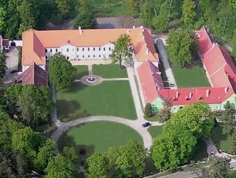 Pohled na historický zámek s oranžovou střechou v českém kraji.