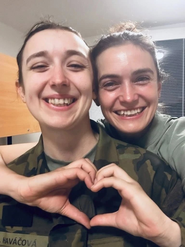 Dvě ženy v uniformě dělají srdce rukama.