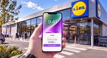 Ruka drží chytrý telefon s aplikací banky před obchodem Lidl.