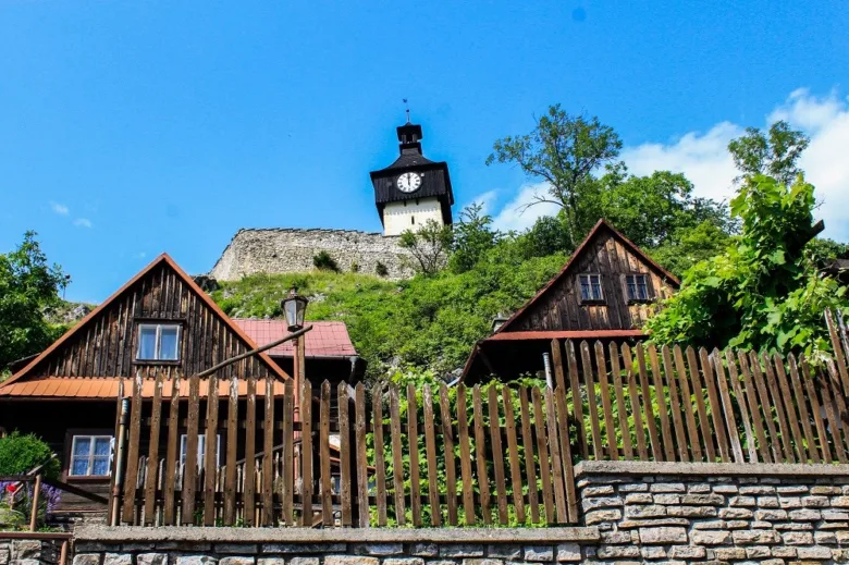 Pohled na historické dřevěné domy s věží ve Štramberku pod modrou oblohou.