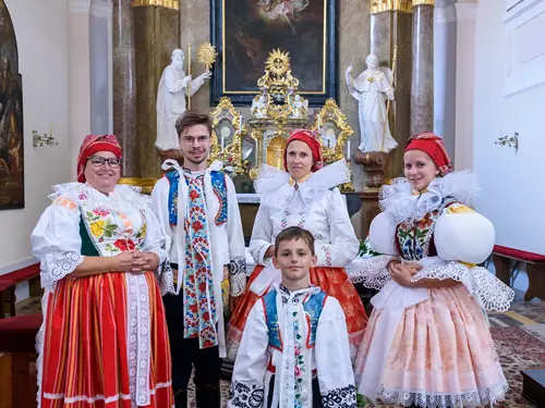 Lidé v lidových kostýmech uvnitř kostela na akci ve Veselí nad Moravou