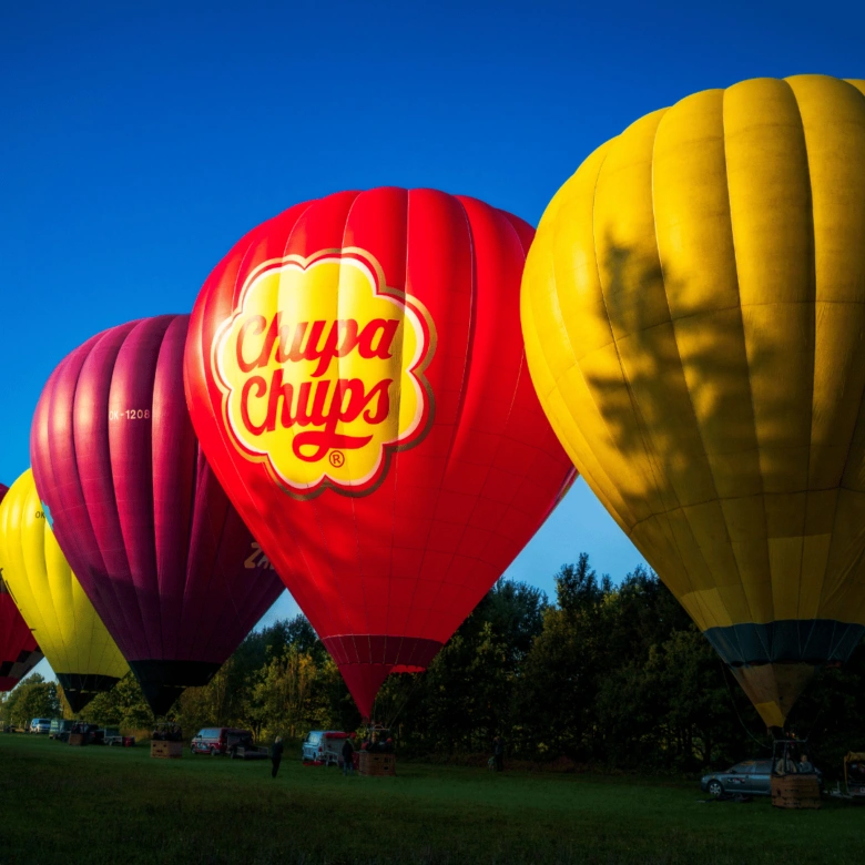 Vzducholodě s logem Chupa Chups na zelené louce pod modrou oblohou.