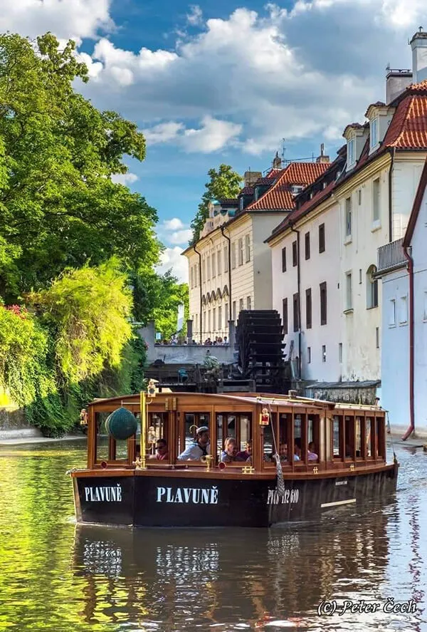 Turistická loď pluje po řece s cestujícími v historickém městě.