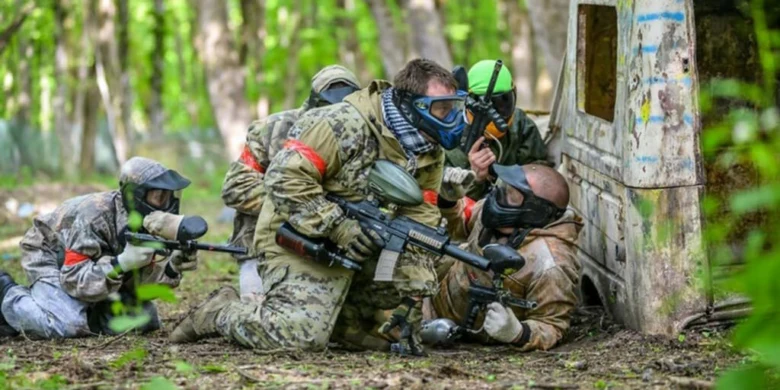 Tým hráčů v maskách se schovává za překážkou na hřišti.