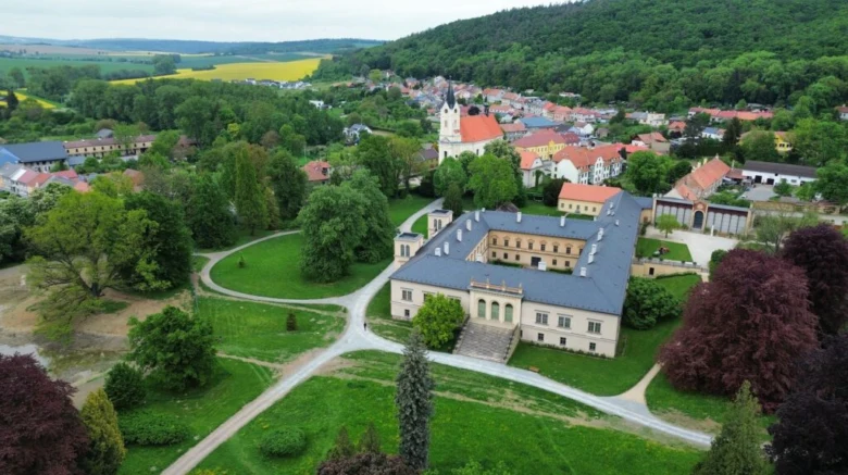 Historické zámek s vesnicí v zelených kopcích jižních Čech.