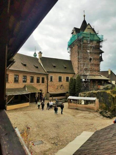 Turisté procházejí dvorem hradu v Lokeci s rekonstruovanou věží.