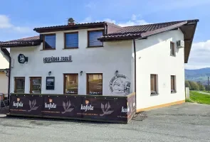 Bílá restaurace s tmavým podkladem v krajině Beskyd