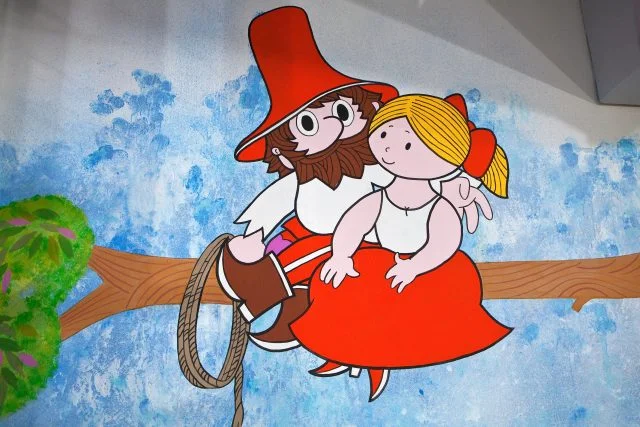 Ilustrace postavy Rumcajse s dívkou Ladou sedícími na větvi.