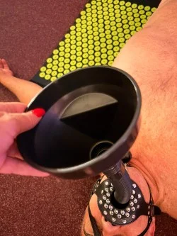 Ruka drží ústní část sex hračky na koberci.