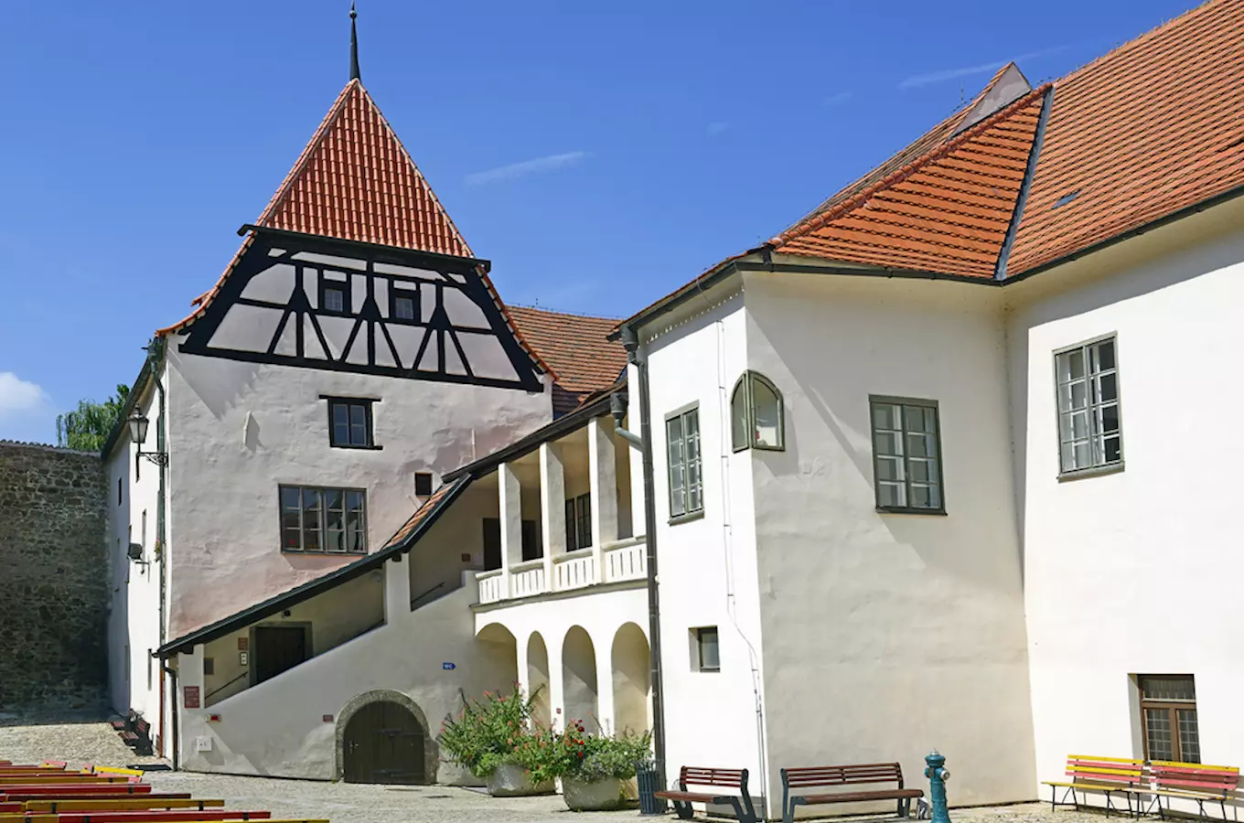 Historická dvůr s bílými budovami v Strakonicích pod modrou oblohou.
