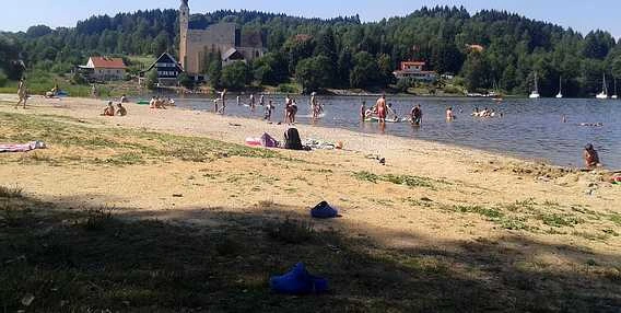 Lidé plavají na břehu jezera v Lipně nad Vltavou.