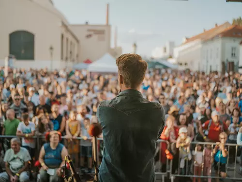 Hudebník vystupuje před davem na venkovním koncertu v Plzni.