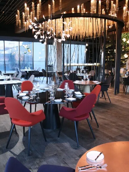 Interiér restaurace s červenými židlemi a závěsným osvětlením.