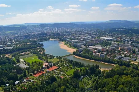 Pohled na město Jablonec nad Nisou s jezerem a okolními lesy.