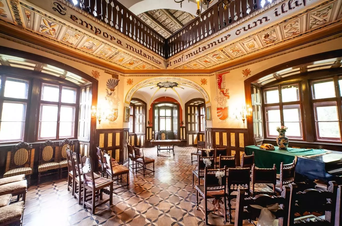 Interiér historického zámku s dřevěnou výzdobou a dlažbou.