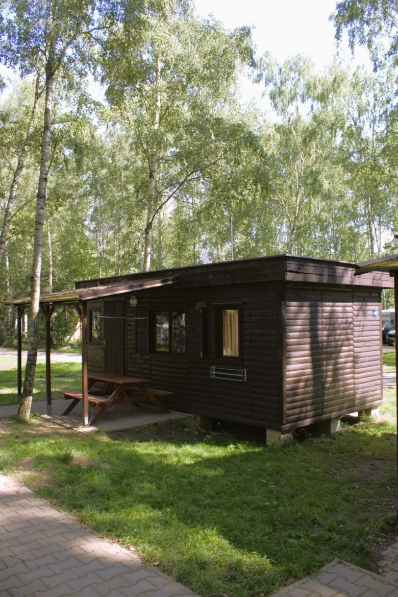 Dřevěný chatička v lese s piknikovým stolem pro ubytování na kempu.