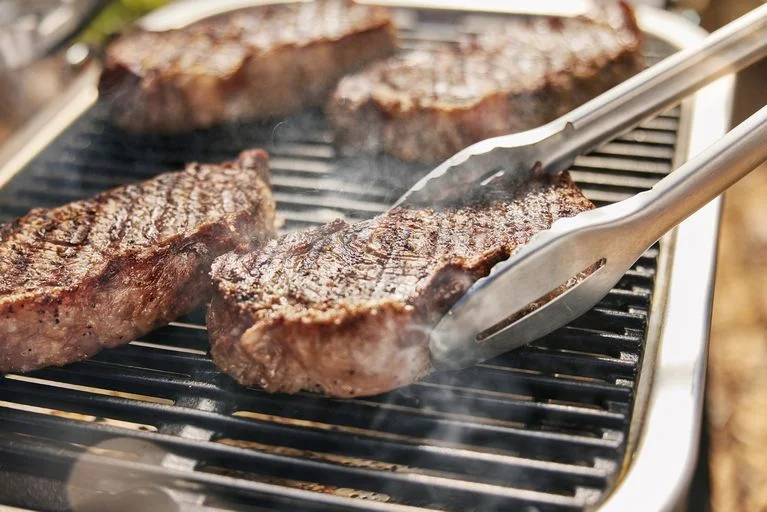 Kusky steaků na elektrickém grilu s výparem.